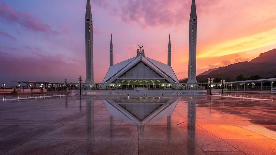 A mosque with four minarets, a large central dome, and a reflection pool.