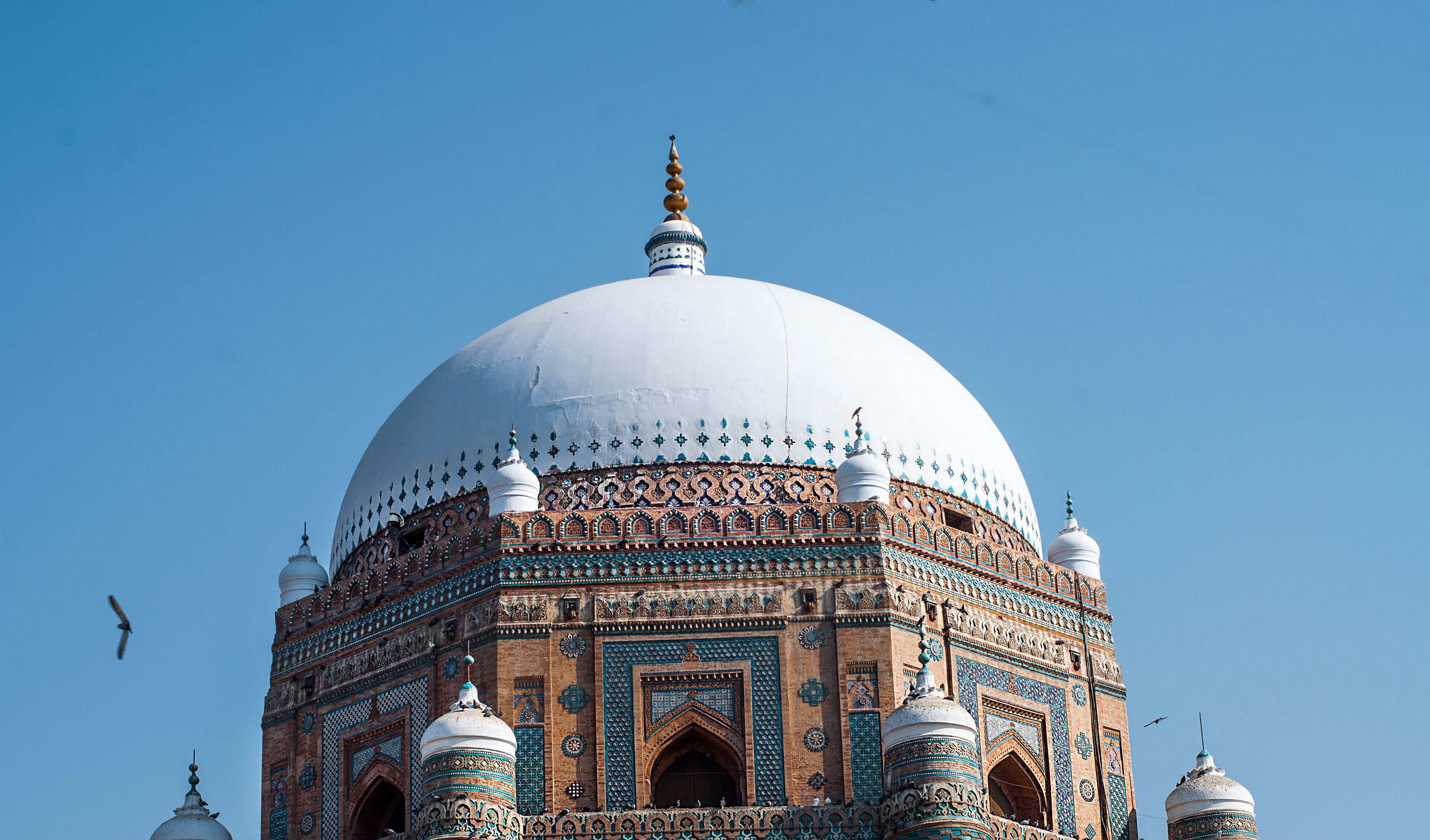 A large white dome with intricate blue and green patterns on a brick building.