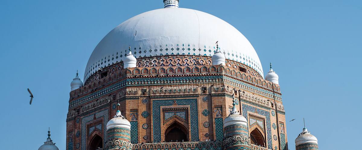 A large white dome with intricate blue and green patterns on a brick building.