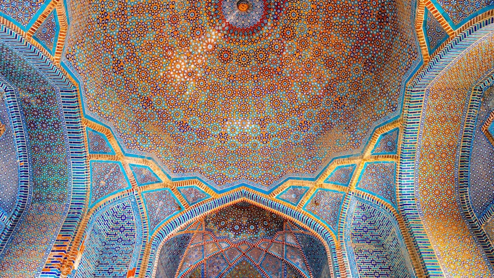 A detailed, ornate ceiling with geometric patterns and a central circular design.