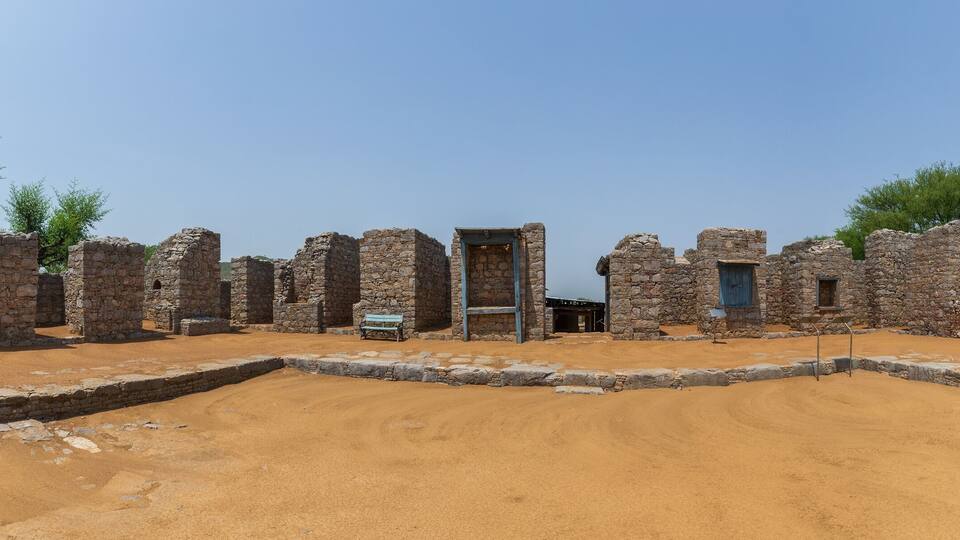 Ancient stone ruins with a central doorway and a bench.