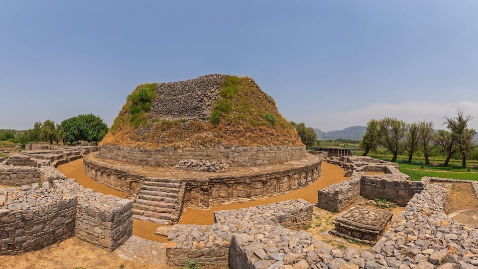 Ancient ruins with stone structures and a central mound.