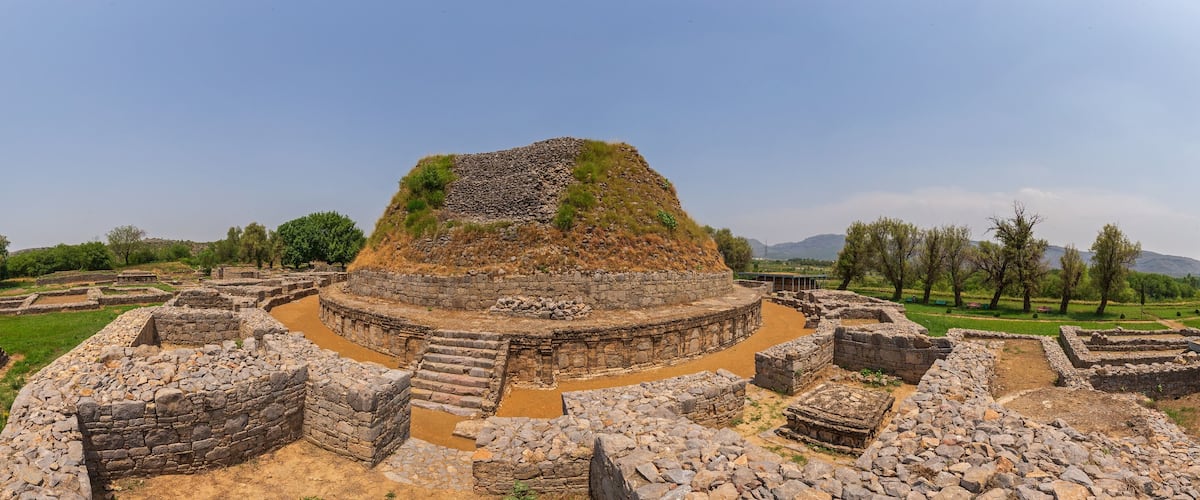 Ancient ruins with stone structures and a central mound.