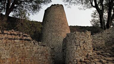 A historical stone structure with a cylindrical tower surrounded by brick walls.