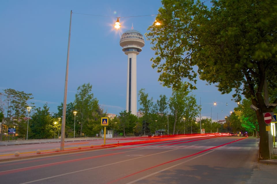 A city street at dusk with a tower in the background.