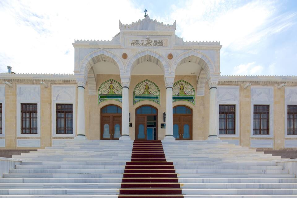 A grand entrance with a staircase leading up to a building with ornate arches and columns.