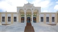 A grand entrance with a staircase leading up to a building with ornate arches and columns.
