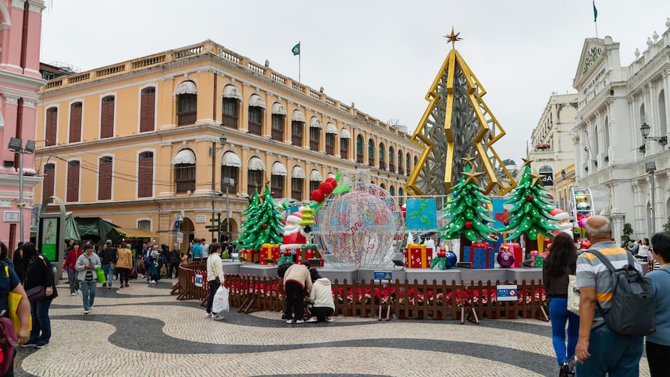 Una plaza pública festiva con un gran árbol de Navidad, un adorno de globo terráqueo y cajas de regalo.
