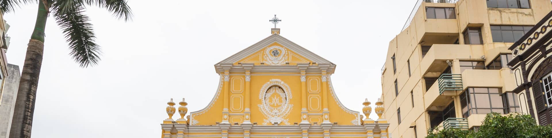 A yellow church with green shutters and ornate white decorations.