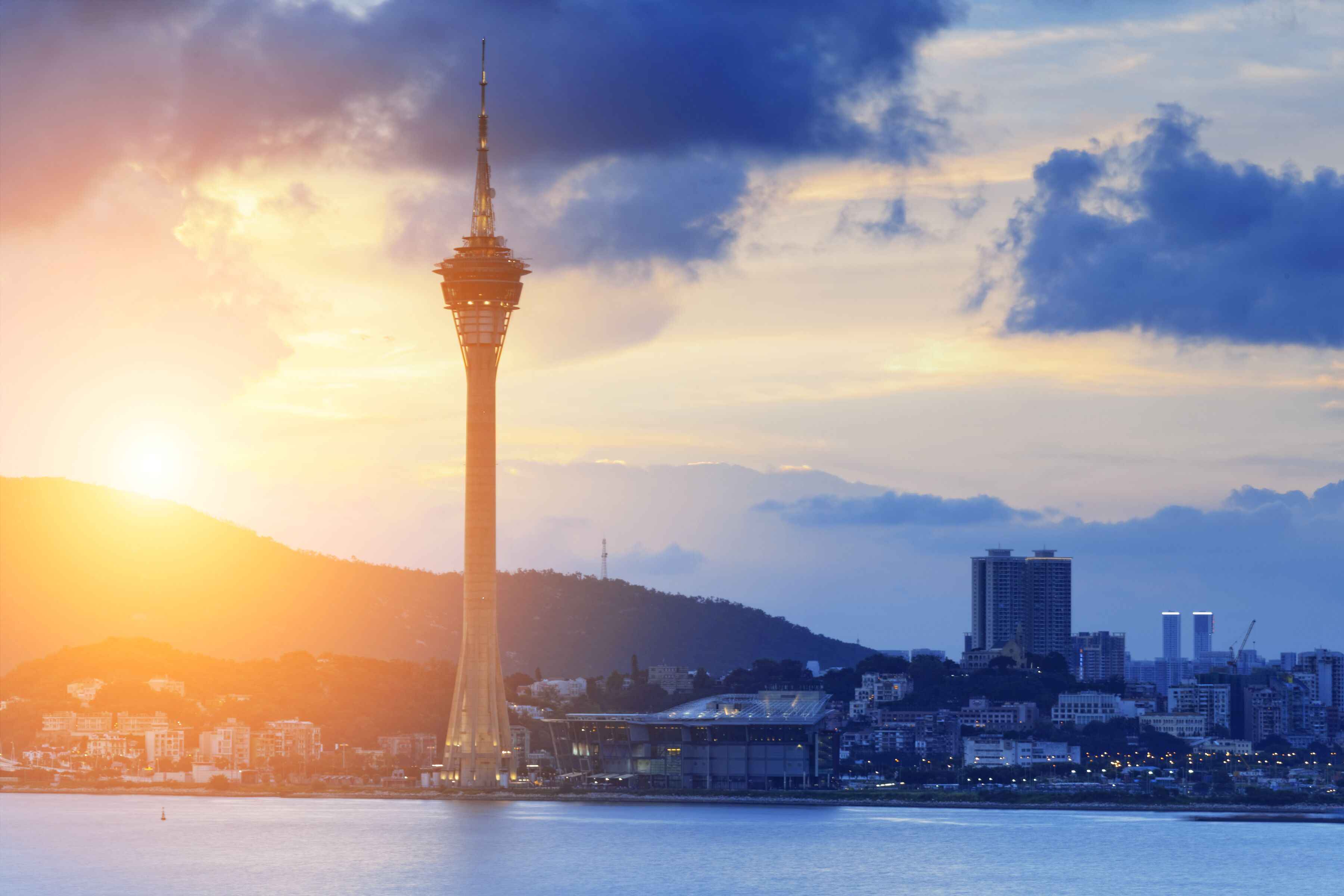A cityscape with a prominent tower against a sunset sky.