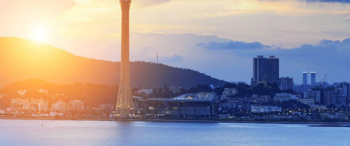 A cityscape with a prominent tower against a sunset sky.