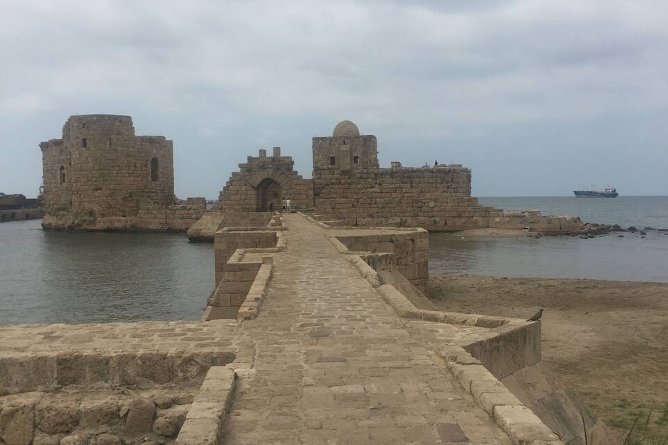 Un sentier de pierre mène à un fort historique doté d’une grande tour et d’une structure en forme de dôme.