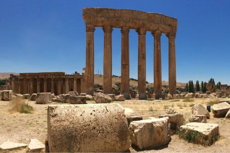 Ancient ruins with large stone columns and scattered stone blocks.
