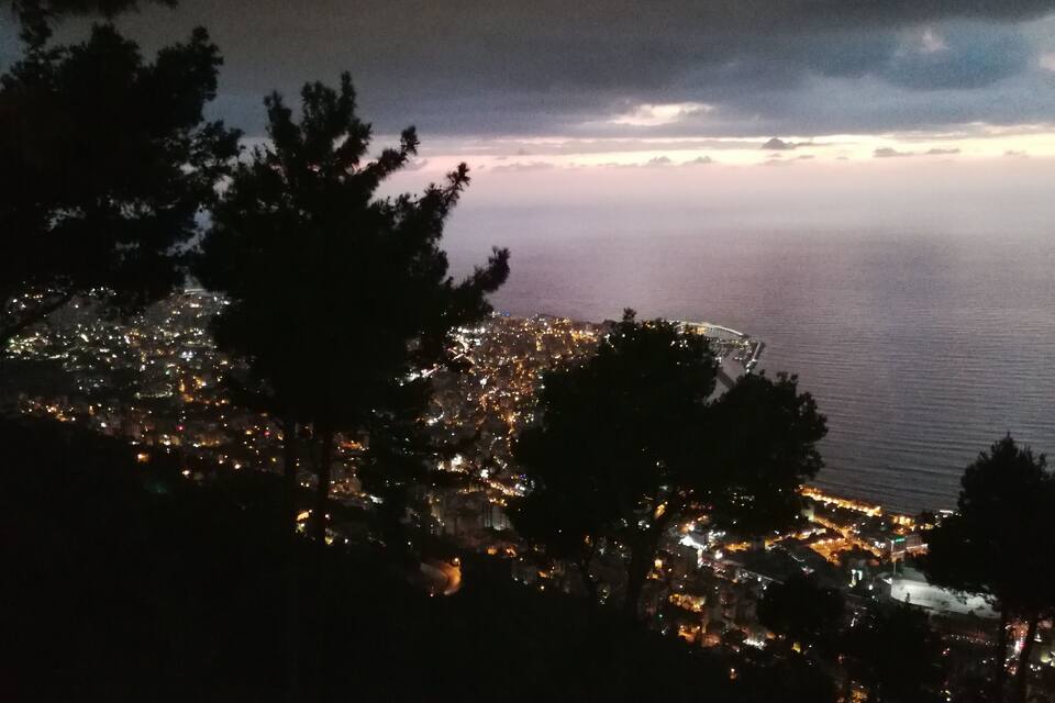 A coastal city at night with a view of the sea and a bridge.