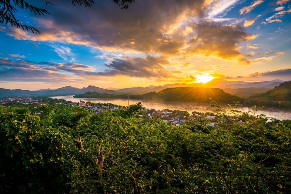 A sunset over a lake with mountains in the background and a town in the foreground.