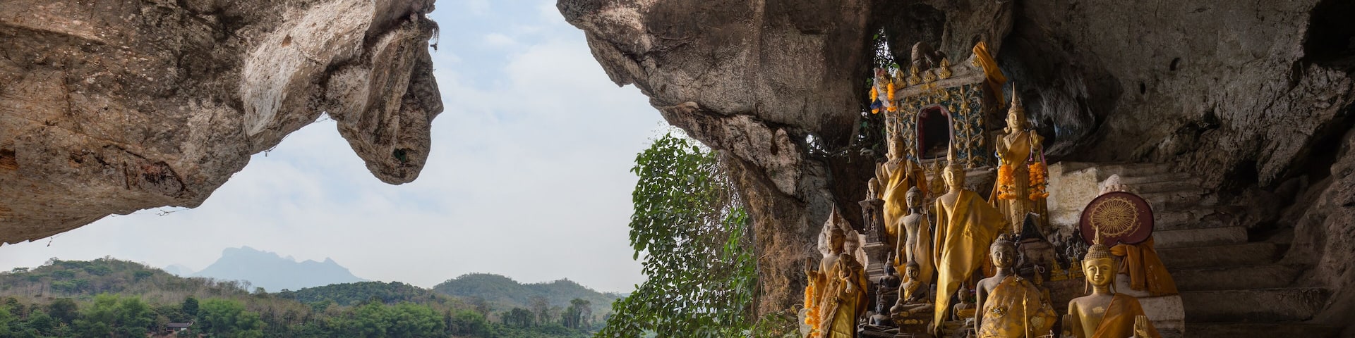 View of the Mekong River and many golden and wooden Buddha statues and religious offerings inside the Tham Ting Cave at the famous Pak Ou Caves near Luang Prabang in Laos., Shutterstock ID 1087763981,