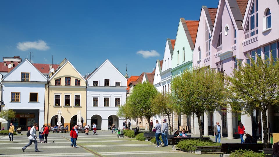 A pedestrian street lined with colorful buildings, a clear blue sky, and people walking.