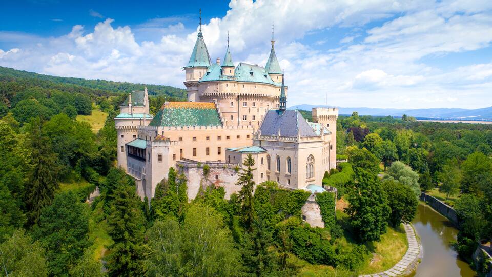 A castle surrounded by lush greenery and a river.