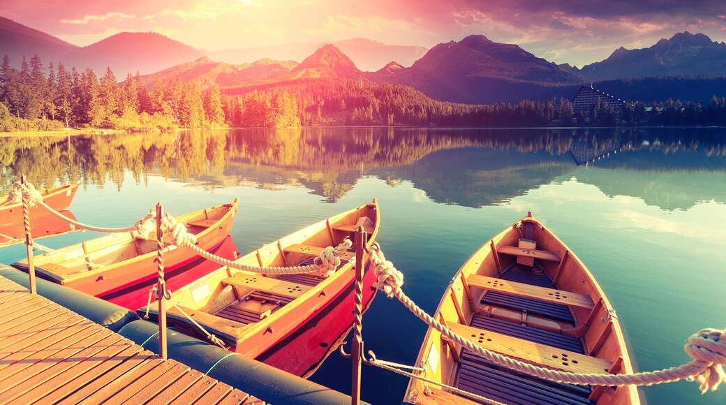 Majestic mountain lake in National Park High Tatra. Dramatic unusual scene. Sky glowing by sunlight. Strbske pleso, Slovakia, Europe. Beauty world. Retro style filter. Instagram toning effect.