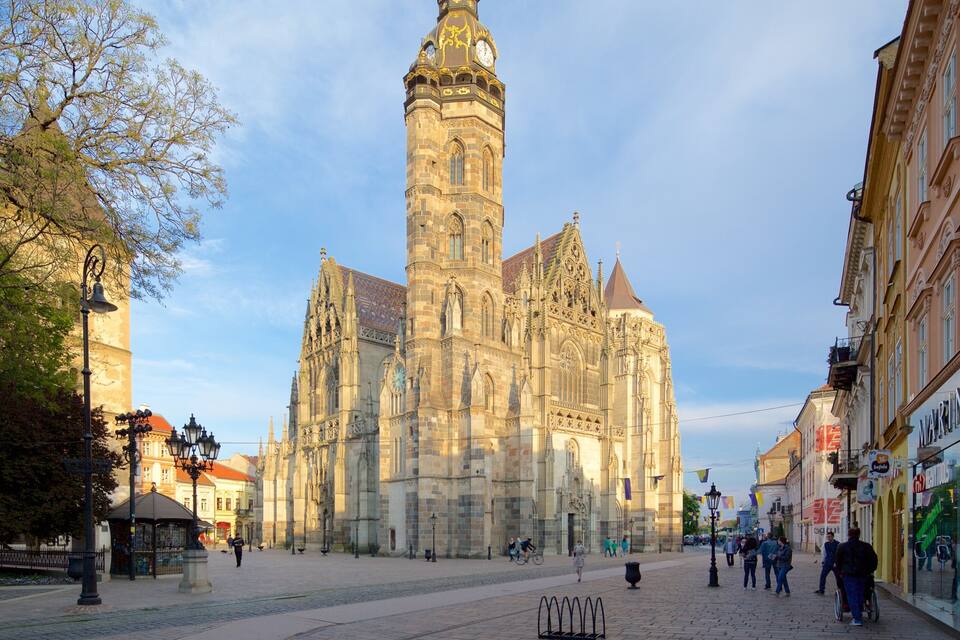 A historic cathedral with intricate architecture, a cobblestone square, and surrounding buildings.
