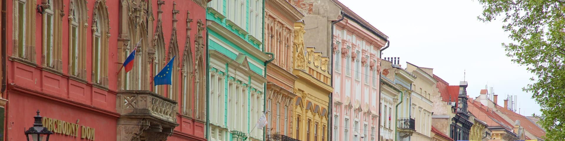 Una calle adoquinada flanqueada por edificios coloridos, banderas y cafés al aire libre.