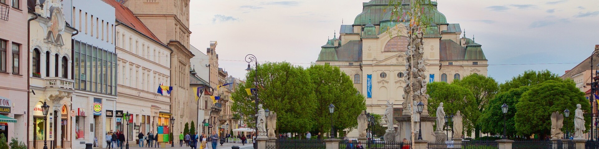 Una plaza adoquinada con una vía de tranvía, edificios históricos y una iglesia grande y ornamentada con cúpula verde.