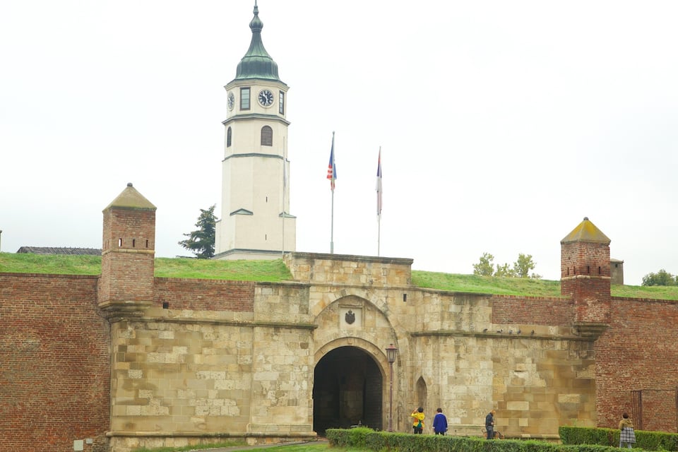 Een historisch fort met een klokkentoren, bakstenen muren en vlaggen.