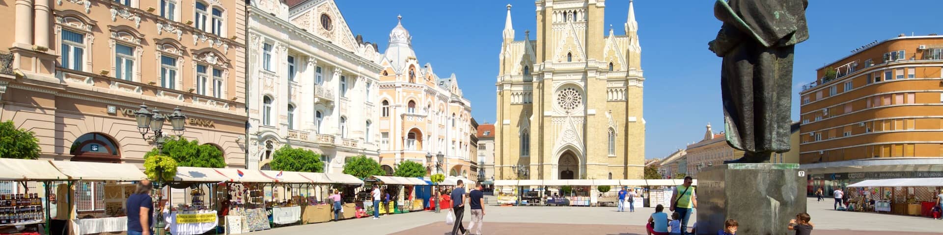 A historic square with a prominent church tower, a statue, and surrounding buildings.