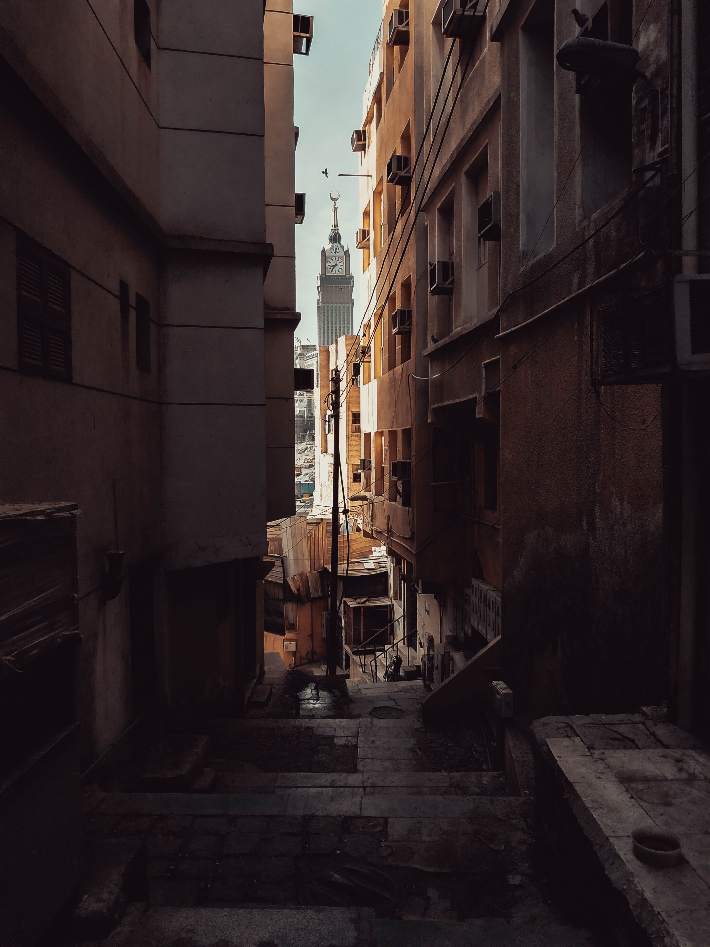 Rich versus Poor. The World's 3rd tallest building, Makkah Clock Tower of the Abraj Al-Bait towers is seen through the street of an old abandoned neighborhood atop a mountain, in Makkah, Saudi Arabia.