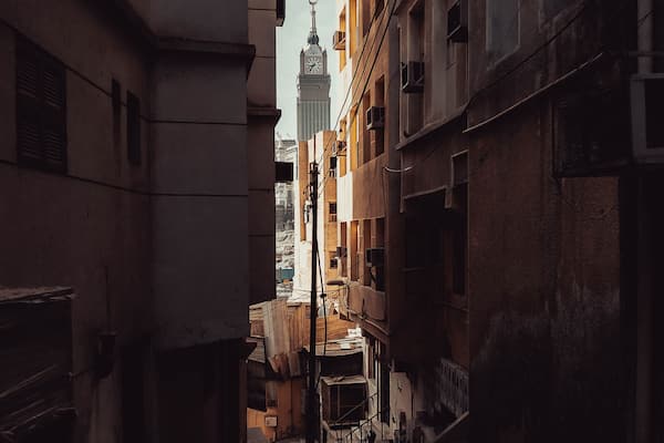 Rich versus Poor. The World's 3rd tallest building, Makkah Clock Tower of the Abraj Al-Bait towers is seen through the street of an old abandoned neighborhood atop a mountain, in Makkah, Saudi Arabia.
