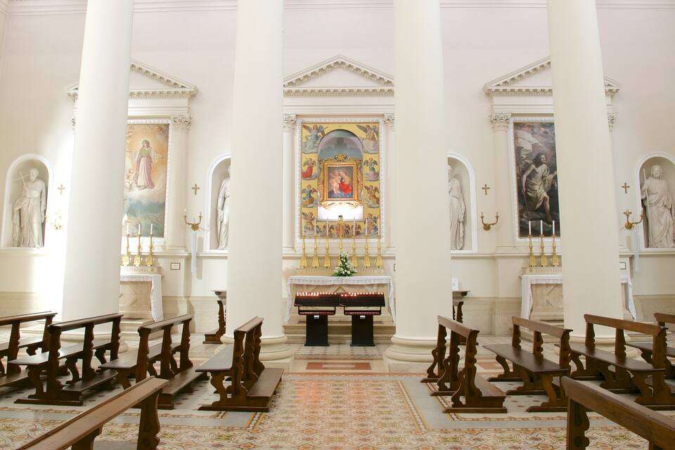 L’intérieur d’une église, avec ses bancs en bois, son autel central et ses statues religieuses.