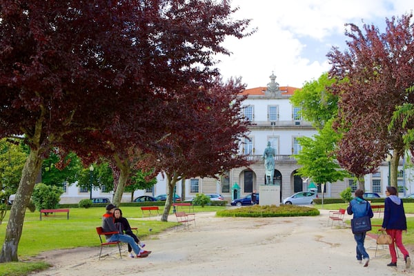 Un parc avec des bancs, des arbres et un bâtiment abritant une statue au centre.