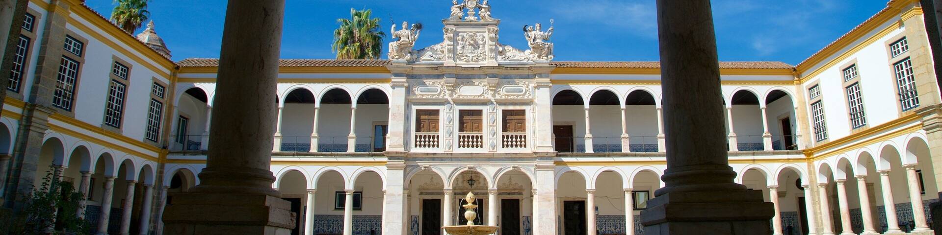Un patio con una fuente, columnas y un edificio con decoraciones ornamentales.