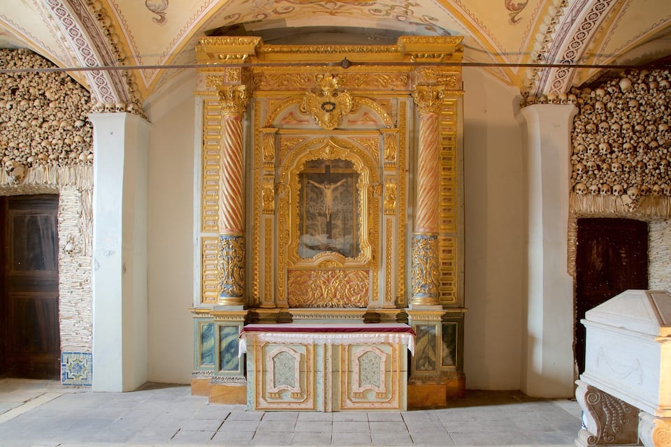 Interior ornamentado de una capilla con un crucifijo, decoraciones doradas y paredes adornadas con calaveras.