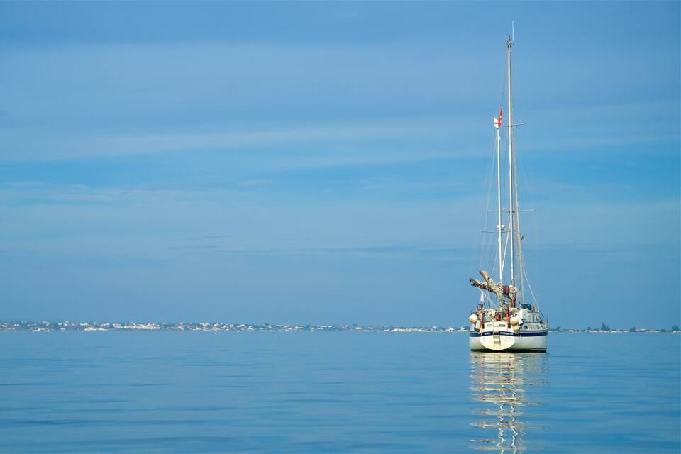 A sailboat on calm waters with a clear sky.