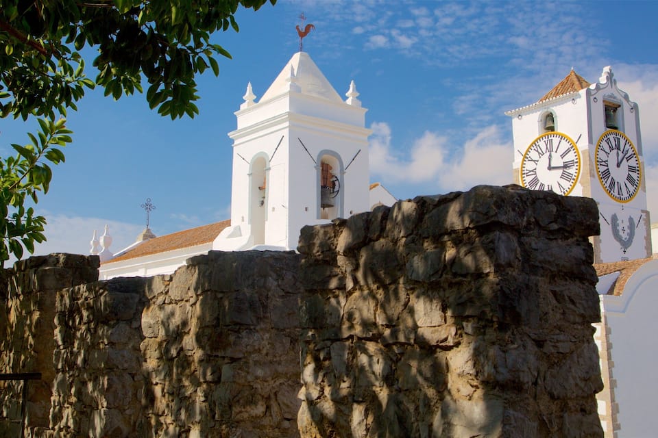 Uma igreja branca com uma torre de sino e um relógio.