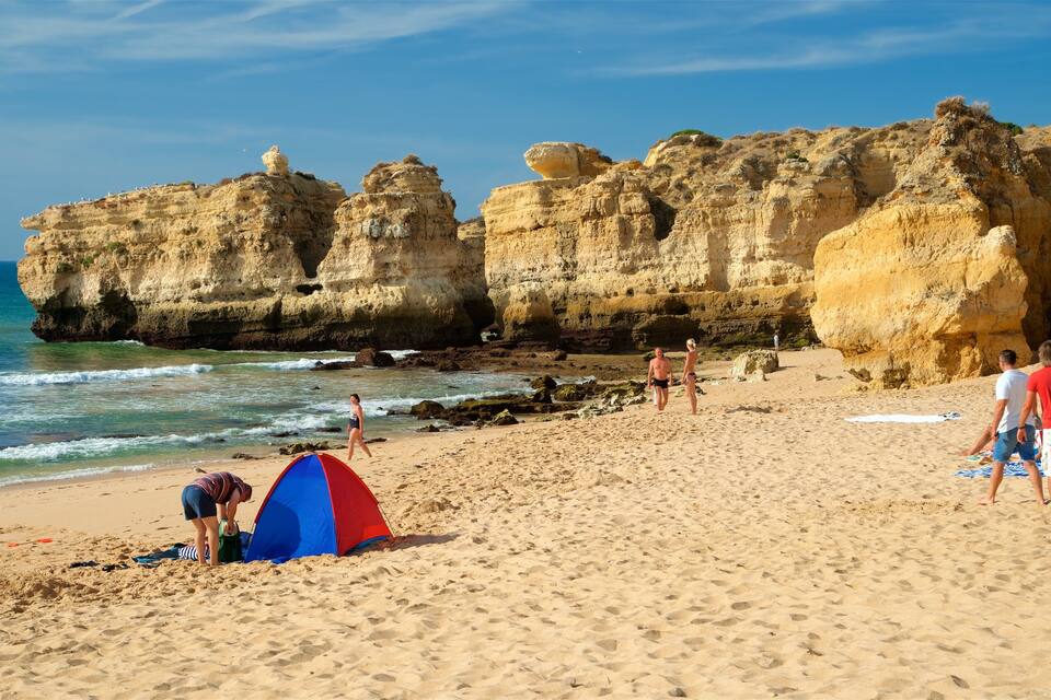 Una spiaggia sabbiosa con scogliere rocciose e un cielo azzurro limpido.