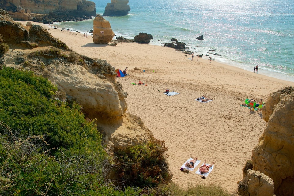 A sandy beach with rocky cliffs and clear blue water.