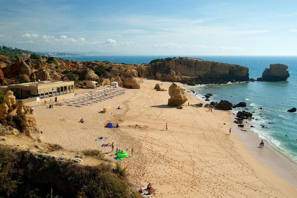 Ein sandiger Strand mit Felsen und einem klaren, blauen Meer.