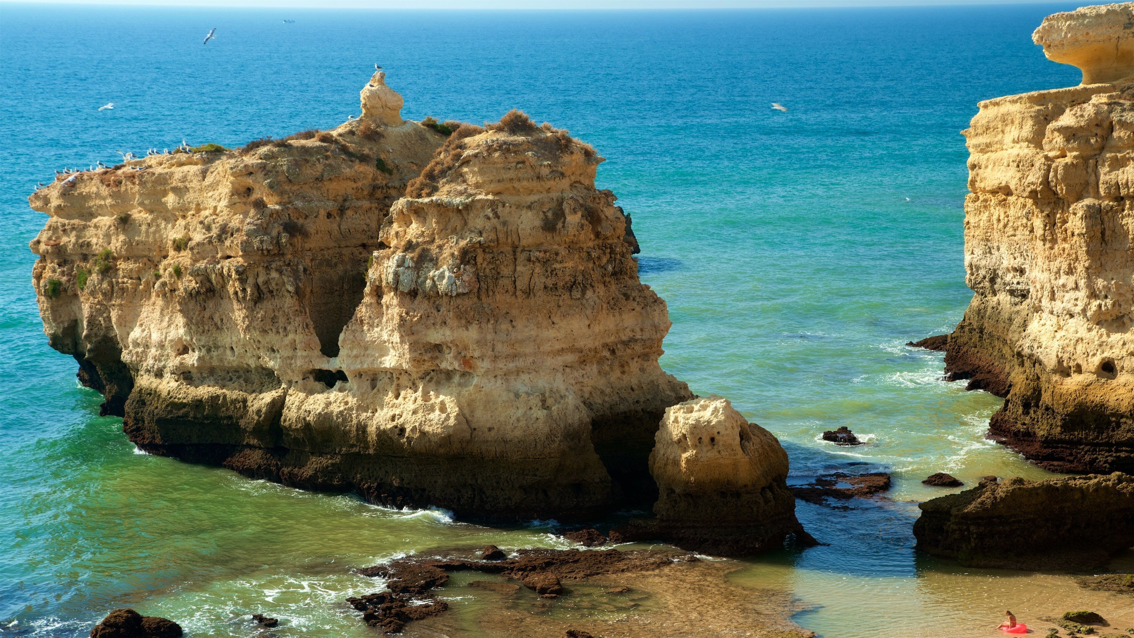 A coastal landscape with rocky formations and clear blue waters.