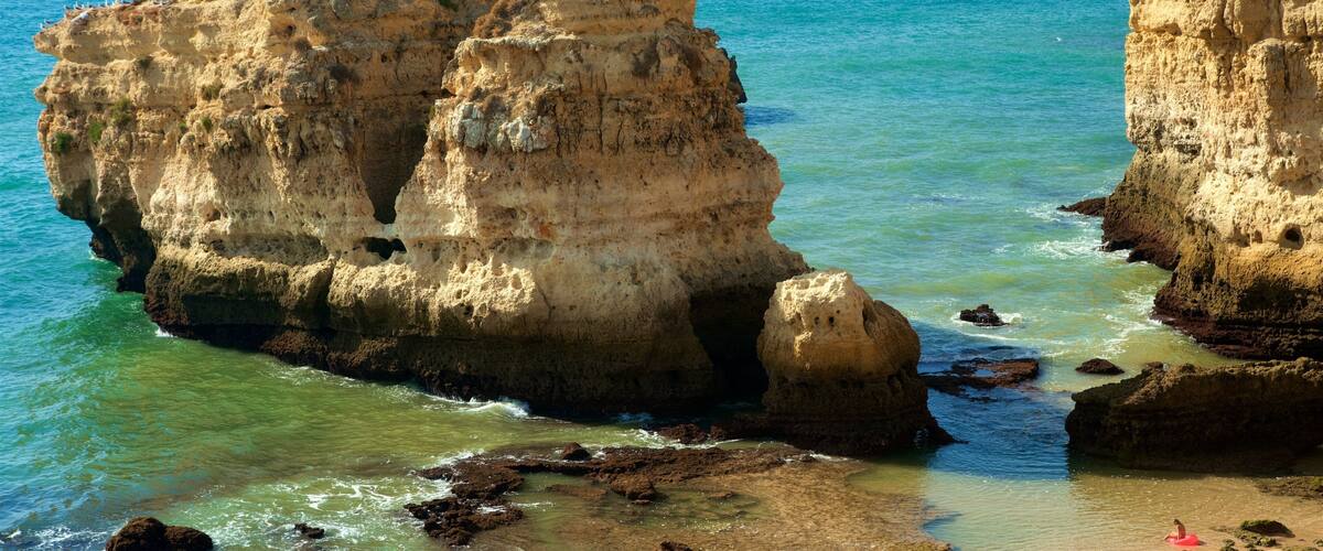 A coastal landscape with rocky formations and clear blue waters.