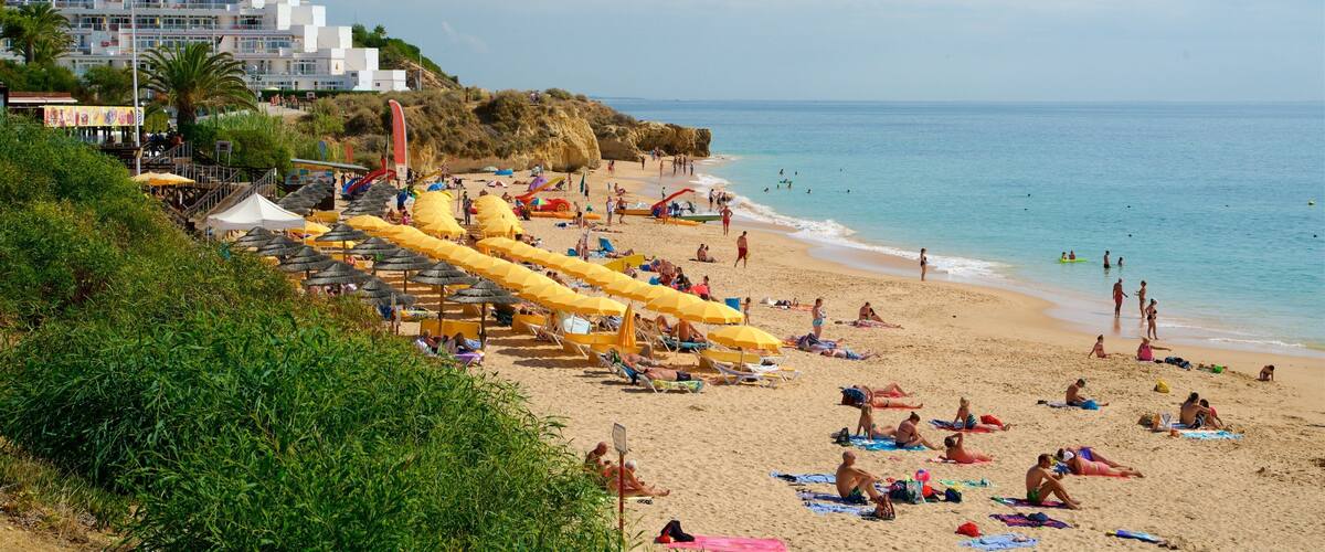 A crowded beach with yellow umbrellas and people sunbathing.