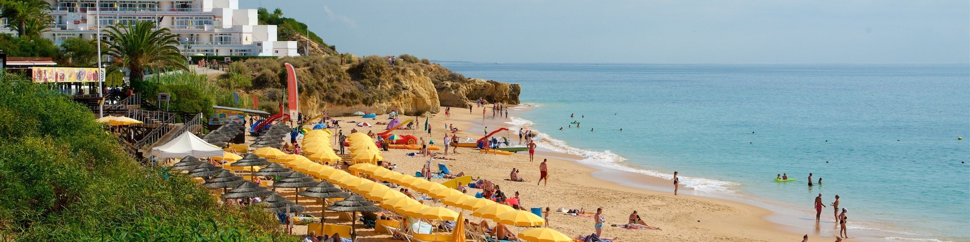 A crowded beach with yellow umbrellas and people sunbathing.