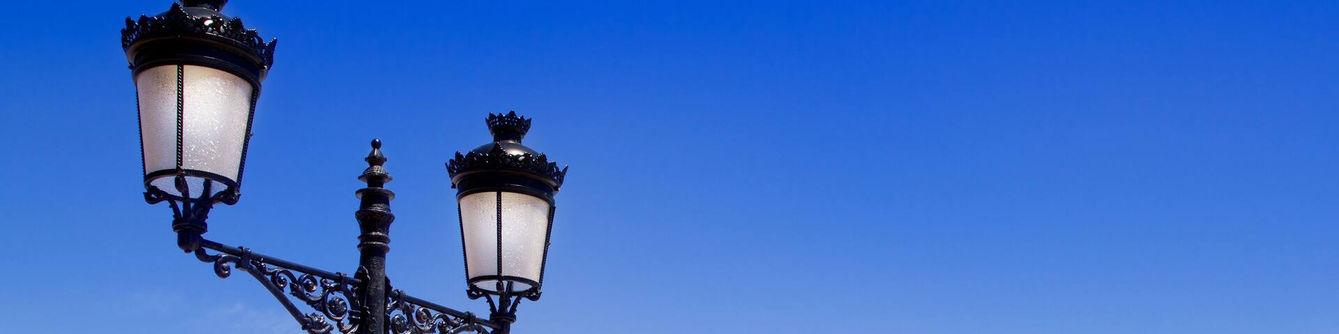 A beach with clear turquoise water, a white building, and a black street lamp.