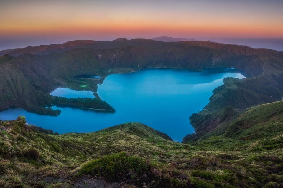 A mountainous landscape with a large lake surrounded by steep cliffs.