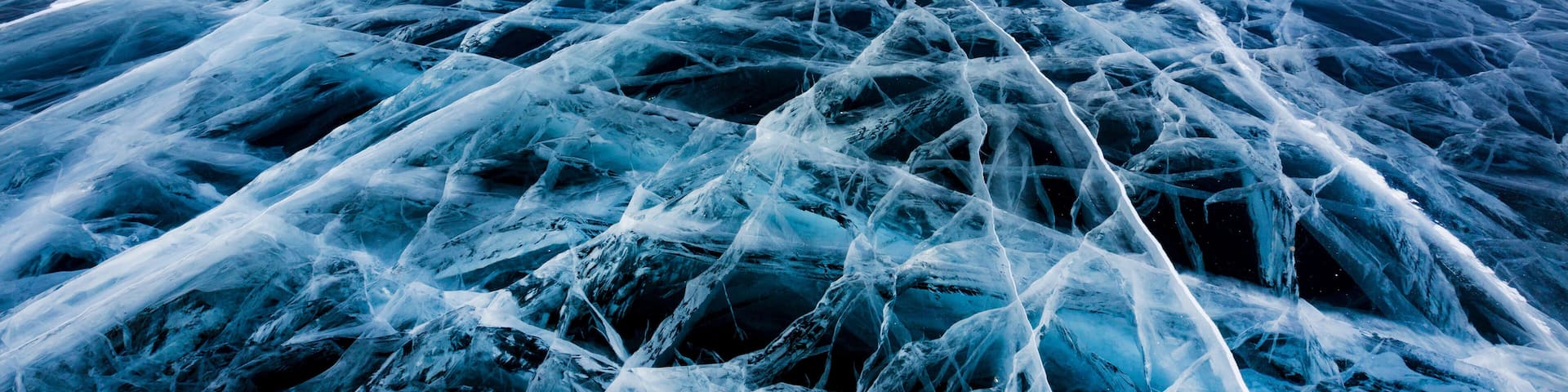 View of beautiful drawings on ice from cracks and bubbles of deep gas on surface of Baikal lake in winter, Russia