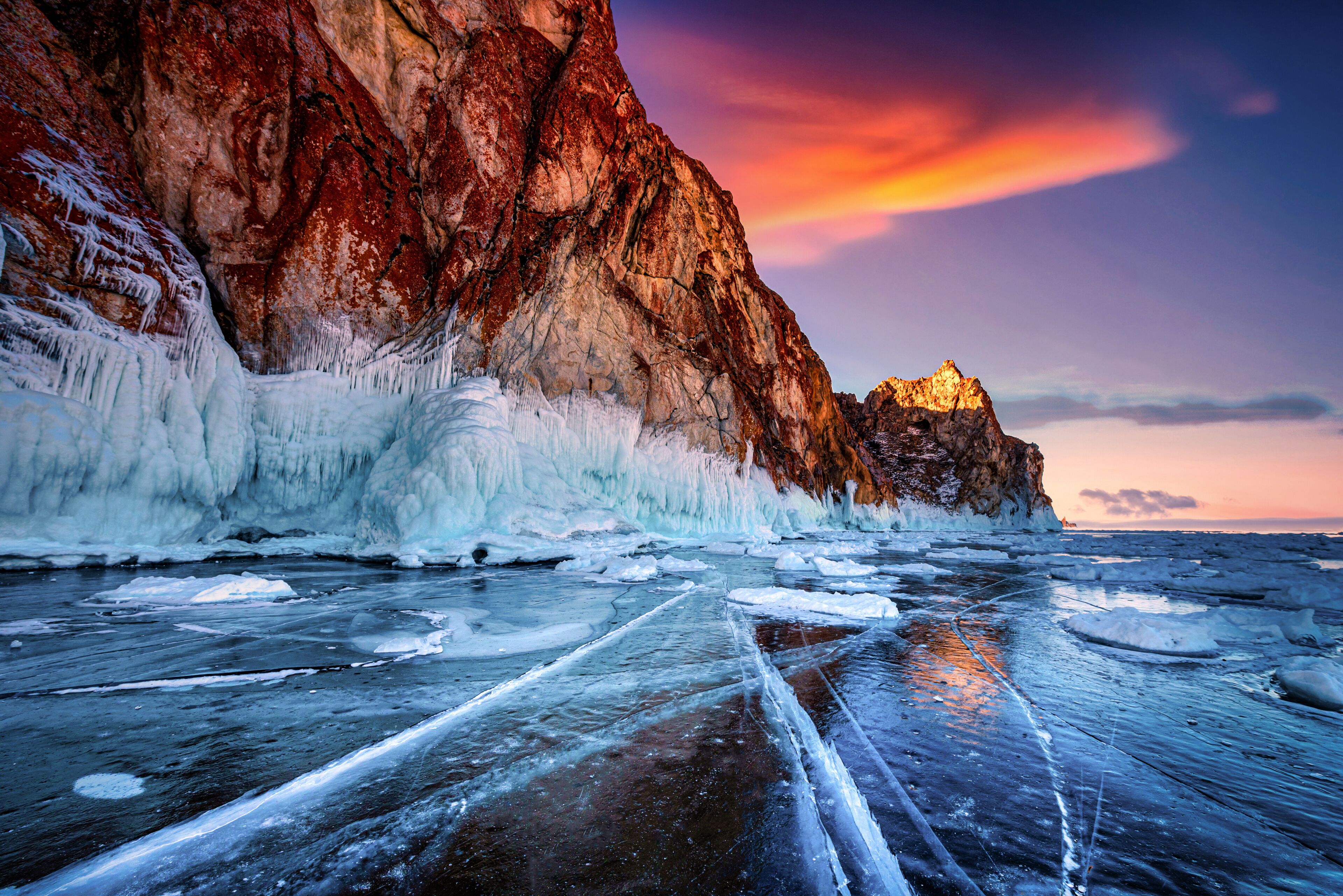 Landscape of Mountain at sunset with natural breaking ice in frozen water on Lake Baikal, Siberia, Russia.