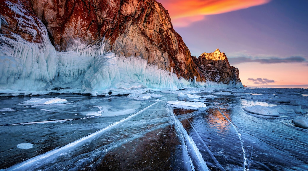 Landscape of Mountain at sunset with natural breaking ice in frozen water on Lake Baikal, Siberia, Russia.