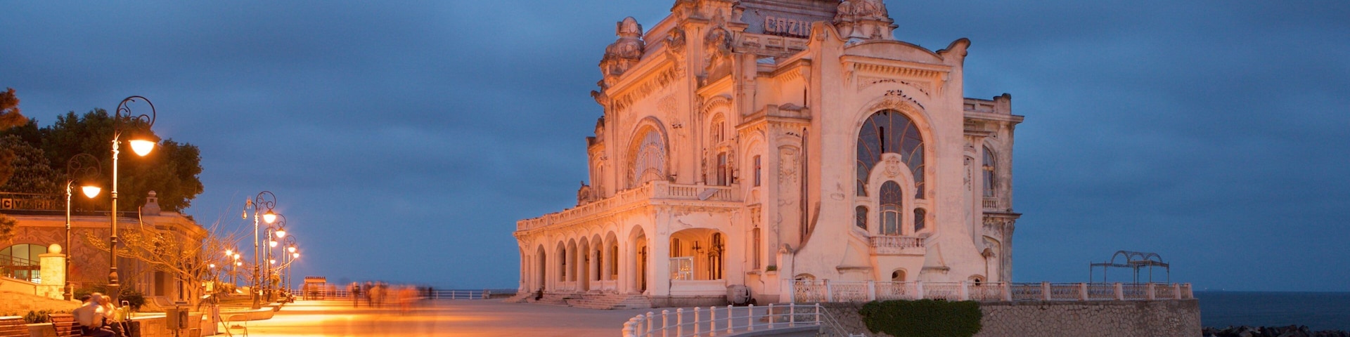 Un edificio histórico con arquitectura ornamentada junto a la costa al atardecer.