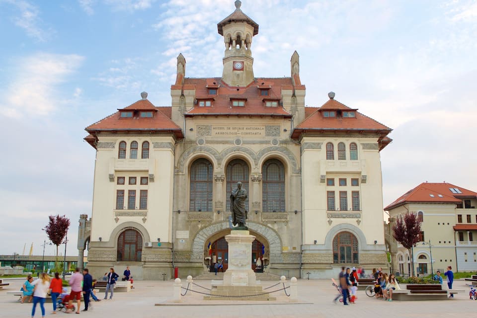 A historic building with a central statue, arched windows, and a clock tower.
